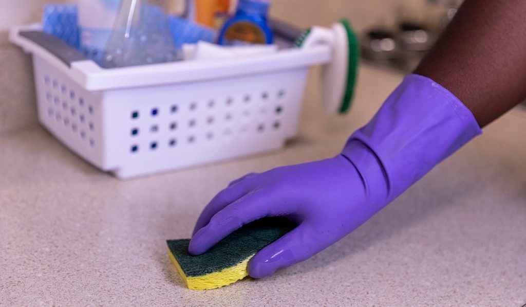 A gloved hand cleaning a kitchen counter